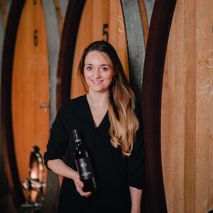Winzerin Tina Netzl aus Göttlesbrunn/Carnuntum mit Weinflasche vor großen Weinfässern