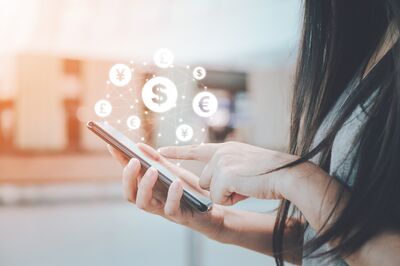 Nahaufnahme einer Person, die über das Smartphone eine Finanztransaktion abwickelt.