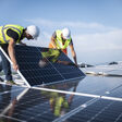 Team of two engineers installing solar panels on roof.