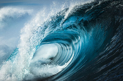 Close up detail of powerful teal blue wave breaking in open ocean on a bright sunny afternoon