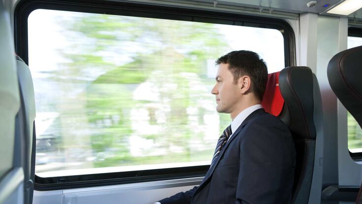 Ein Mann im Anzug reist mit der Bahn.
