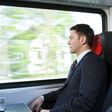Ein Mann im Anzug reist mit der Bahn.