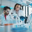 Modern Medical Research Laboratory: Portrait of Latin and Black Young Scientists Using Microscope, Digital Tablet, Doing Sample Analysis, Talking. Diverse Team of Specialists work in Advanced Lab