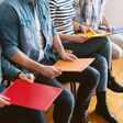 Mehrere Bewerberinnen und Bewerber sitzen in einer Reihe bei einem Jobinterview, Gesichter nicht sichtbar, in den Händen Bewerbungsmappen