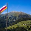 Kärntens Landesflagge weht vor Hintergrund mit Bergen im Lesachtal.