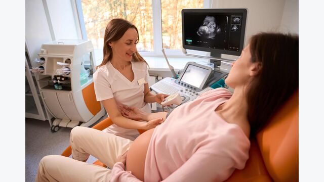 Eine Gynäkologin oder Krankenpflegerin führt einen Ultraschall bei einer Schwangeren durch