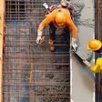 Zwei Bauarbeiter gießen Beton auf einer Baustelle.