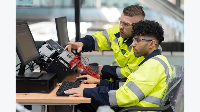 Zwei männliche Techniker sitzen an einem Computertrainingsprogramm im Automatisierungsbereich.