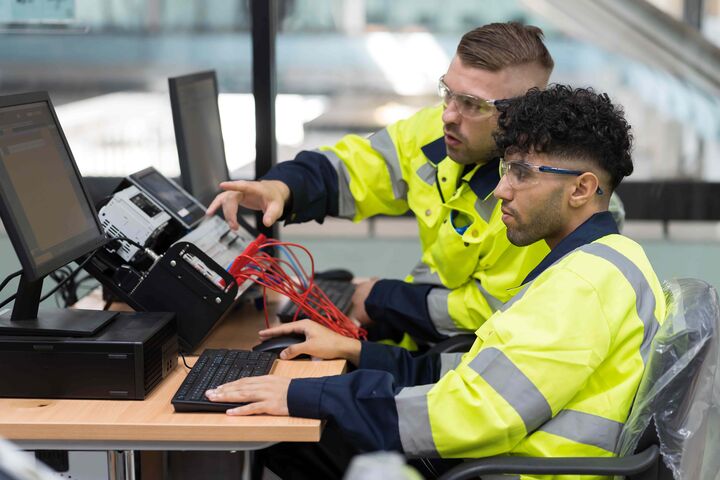 Zwei männliche Techniker sitzen an einem Computertrainingsprogramm im Automatisierungsbereich.