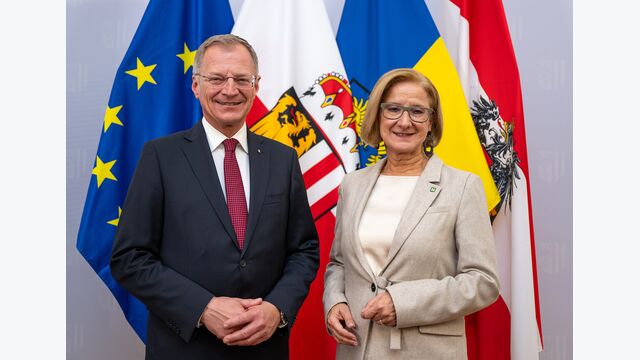 Oberösterreichs Landeshauptmann Thomas Stelzer und Niederösterreichs Landeshauptfrau Johanna Mikl-Leitner posieren vor Bundeslandflaggen.