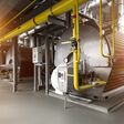 Moderner industrieller Heizkesselraum, ausgestattet für den Heizprozess mit Heizgas-Kessel, Rohrleitungen und Ventilen.