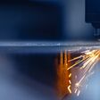 Blue color Laser CNC cut of metal with light spark, technology modern industrial.