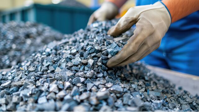 Nahaufnahme von behandschuhten Händen, die zerkleinerte Metallstücke sortieren und handhaben, vermutlich für industrielle oder fertigungstechnische Prozesse.