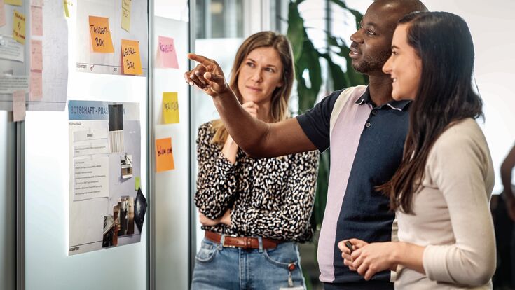 © Blum 3 Mitarbeiter vor Wand mit Post-its