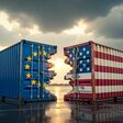 Zerbrochene Schiffscontainer mit den Flaggen der USA und der EU, die Handelskrieg und Zölle symbolisieren. KI-generiert.