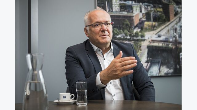 Elmar Hartmann, Präsident der Industriellenvereinigung (IV) Vorarlberg, sitzt sprechend an einem Tisch, neben sich ein Glas Wasser und eine Karaffe.