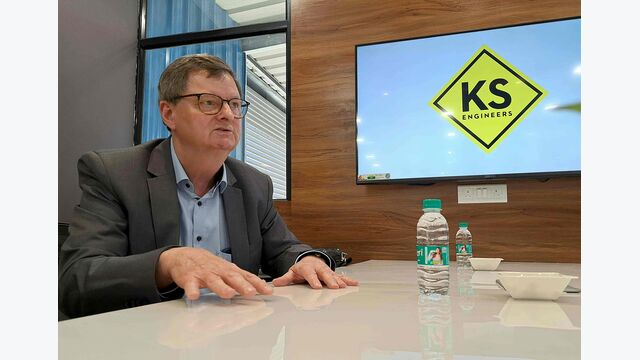 Geschäftsführer Wolfram Rossegger bei KS Engineers in Pune, Indien, an einem Ttisch sitzend und sprechend.