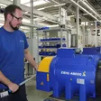 Techniker bei Ziehl-Abegg arbeitet an einer blauen Aufzugsmaschine.