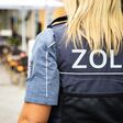 Eine Zollbeamtin in entsprechend gekennzeichnet Uniform mit langen blonden Haaren von hinten, Gesicht nicht sichtbar