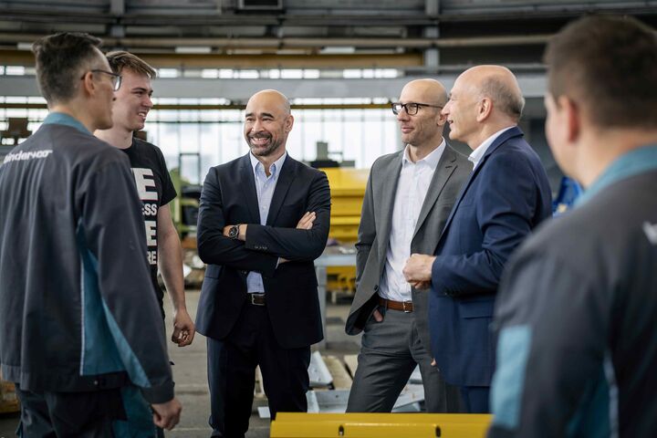 Jörg Rosegger, neuer Vorstandsvorsitzender von Binder+Co, steht lächelnd in einer Runde mit mehreren Kollegen.