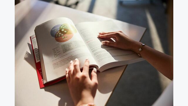 Hände halten die nichtfinanzielle Erklärung 2024 der ÖBB auf einem Tisch aufgeschlagen.