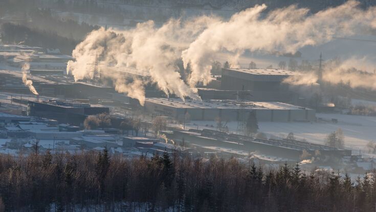 © Adobe Stock/hebinosss Eine stark qualmende Industrieanlage in Nüziders, Vorarlberg.