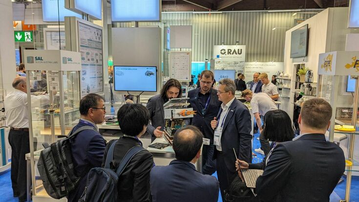 © Silicon Austria Labs Mehrere Menschen um einen Messestand von Silicon Austria Labs (SAL)