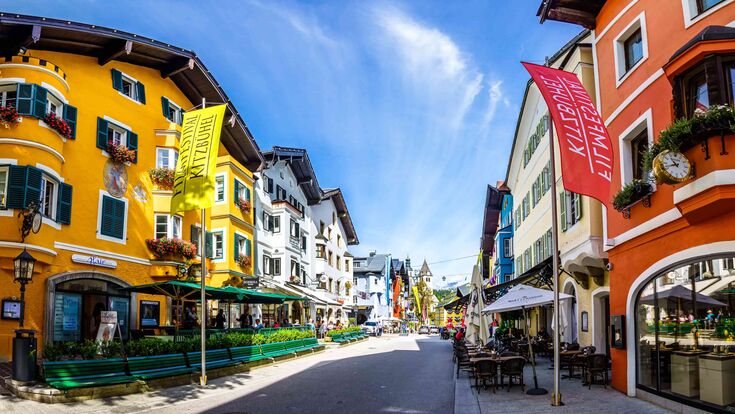 © Adobe Stock/fottoo Fischaugenansicht auf eine Gasse mit Geschäften in der Altstadt von Kitzbühel, Tirol, bei blauem Himmel.
