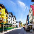 Fischaugenansicht auf eine Gasse mit Geschäften in der Altstadt von Kitzbühel, Tirol, bei blauem Himmel.