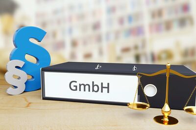 © Adobe Stock/MQ-Illustrations Illustration von Rechtsform: "GmbH" geschrieben auf Ringmappe, daneben Paragrafen-Symbole