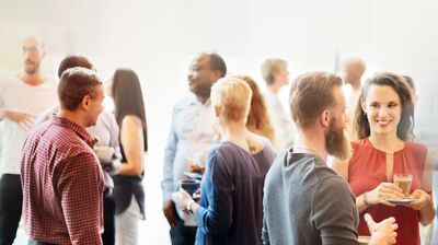 © Rawpixel.com Networking-Event mehrerer junger Menschen, stehend und mit Getränken.