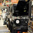 Eine Reihe schwarzer Mercedes G-Klasse in der Produktion, im Hintergrund verschwommen Techniker.