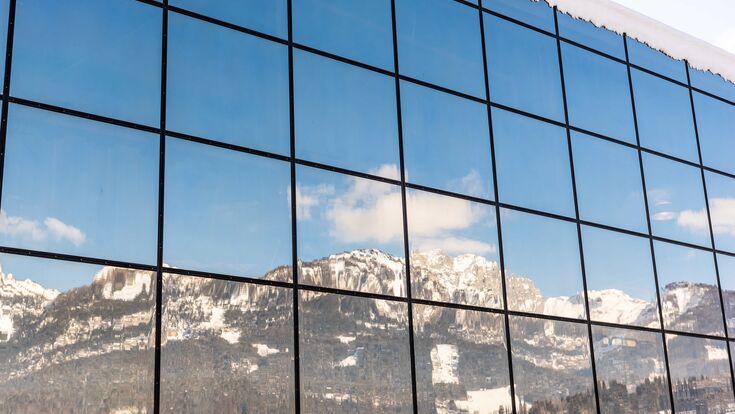 © Adobe Stock/mckornik Spiegelung der Berge in einem Glasgebäude – Dachsteinmassiv, Bezirk Liezen, Steiermark, Österreich