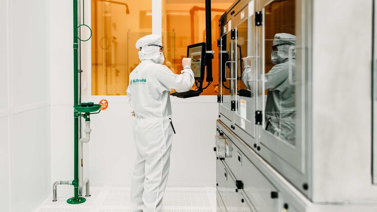 Forscher oder Forscherin in weißer Schutzkleidung in einem Labor der Silicon Austria Labs.