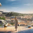 junge Frau blickt durch Fensterwand auf eine schöne, futuristische Form von Graz