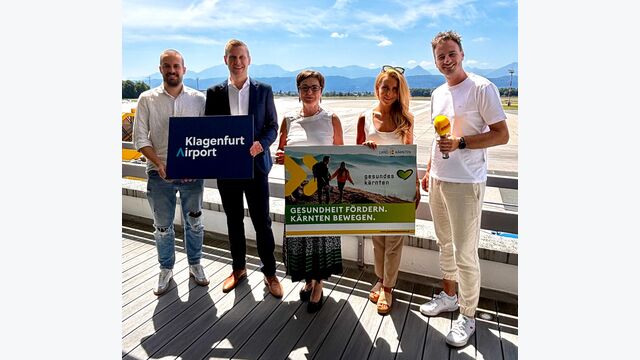 Matteo Scheucher (Mediaberater, Antenne Kärnten), Maximilian Wildt (Geschäftsführer Klagenfurt Airport), Beate Prettner, Sarah Pucker (UA-Leitung Gesundheitsförderung), Andreas Sollbauer (Teamleitung Marketing Kärnten, Antenne Kärnten) bewerben Klagenfurt Airport Night Run 2025 mit Schildern.