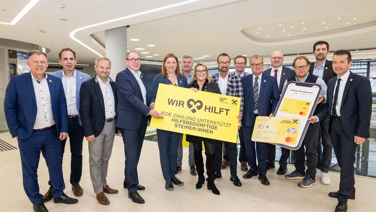 Große Gruppe der  Raiffeisen Steiermark präsentiert mit großem Schild den Sozialfonds „WIR hilft“