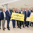 Große Gruppe der  Raiffeisen Steiermark präsentiert mit großem Schild den Sozialfonds „WIR hilft“