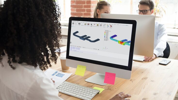 Rückenansicht auf eine Frau an einem Schreibtisch, die am Computer an technischen 3D-Visualisierungen arbeitet.