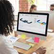 Rückenansicht auf eine Frau an einem Schreibtisch, die am Computer an technischen 3D-Visualisierungen arbeitet.