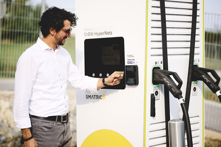 Mann zahlt bei E-Auto-Ladesäule mit Kreditkarte