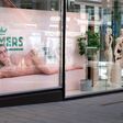 Außenansicht einer Palmers-Filiale in Wien mit vorbeigehender Passantin von hinten