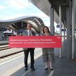 ÖBB-Geschäftsführer Ewald Jantscher und LRin Claudia Holzer halten auf einem Bahnhof ein rotes Schild in die Höhe, mit Aufschrift: "Modernisierung Steirische Westbahn"