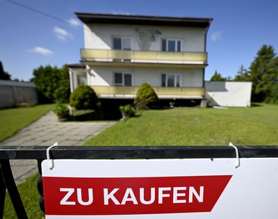 Außenansicht von vorne auf ein Einfamilienhaus in Gänserndorf, Österreich, mit "Zu Kaufen"-Schild am Anfang des Grundstücks.