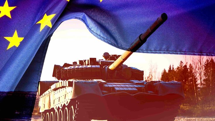 Ein Panzer fährt unter einer gelüpften EU-Flagge durch.
