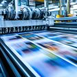 KI-generiertes Bild zeigt schnell arbeitende Druckerpresse, die eine bunte Zeitung druckt.