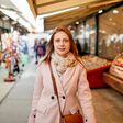 Eine junge lächelnde Frau macht Einkäufe am Wiener Naschmarkt.