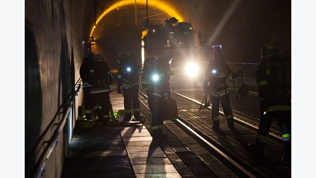 tunnelübung koralmtunnel: mehrere einsatzkräfte leuchten im dunkeln mit taschenlampen