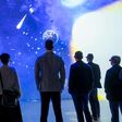 Mehrere Menschen blicken beim DNA Summit 2025 bei Wacker Neuson mit VR-Brillen auf eine große Leinwand mit Meteoriten.