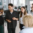 Mehrere junge Menschen stehen an der TU Graz um ein Whiteboard und lachen.